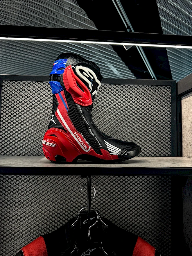 Motorradstiefel in Honda Farben von Alpinestars, darunter eine Lederkombi – Töff Bekleidung